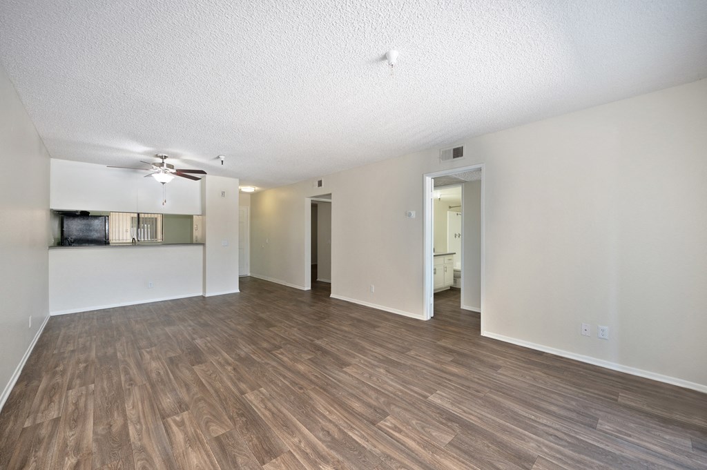 a 2-bedroom apartment living room and kitchen with wood flooring and a ceiling fan