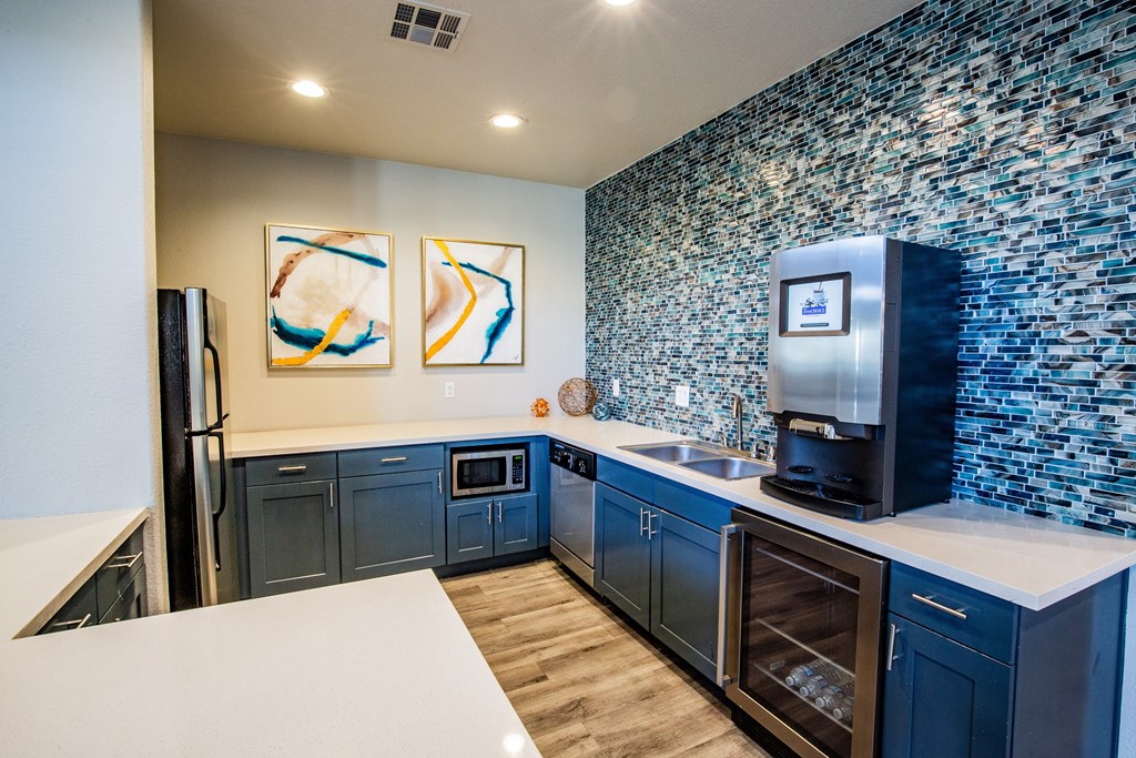 Club house kitchen with a white counter top and blue cabinets.
