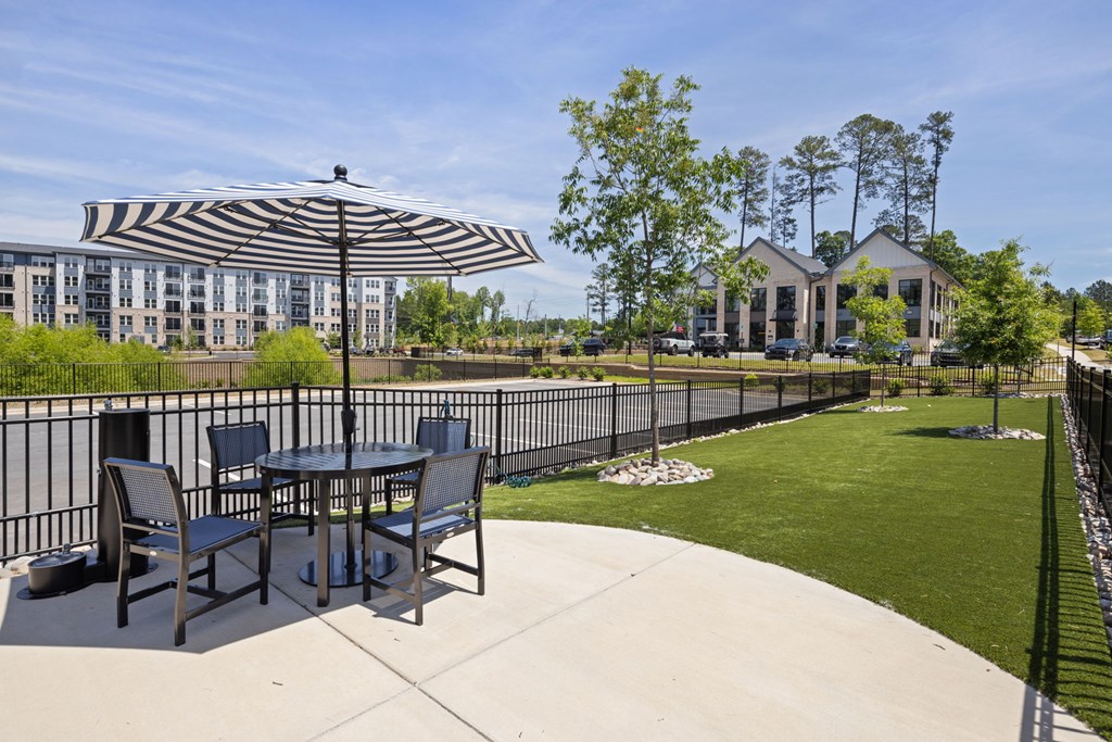 A patio with a table and chairs under a striped umbrella.