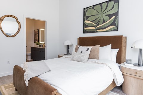 A bedroom with a large bed and a painting on the wall.