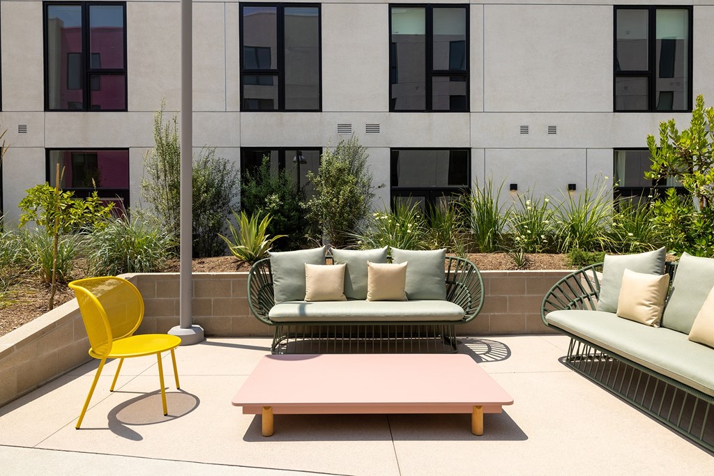 A yellow chair sits on a patio with a couch and a table.
