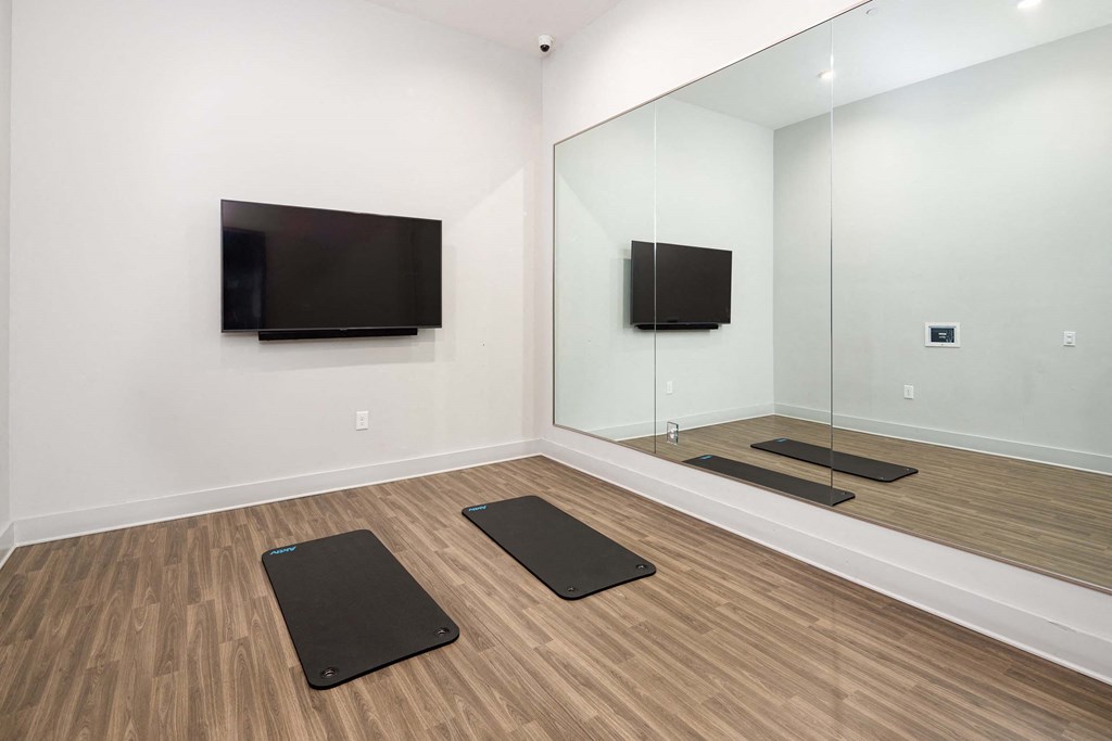 a yoga room with mirrors and yoga mats and a television on the wall