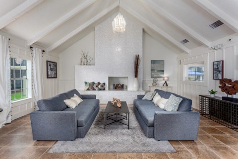 A living room with grey couches and a white fireplace.