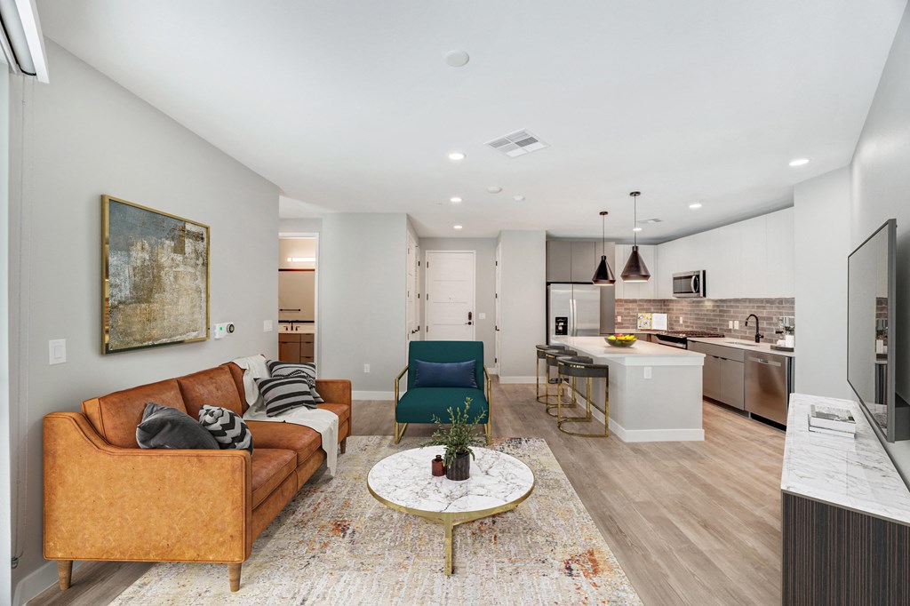 a living area with a couch coffee table and a kitchen in the background