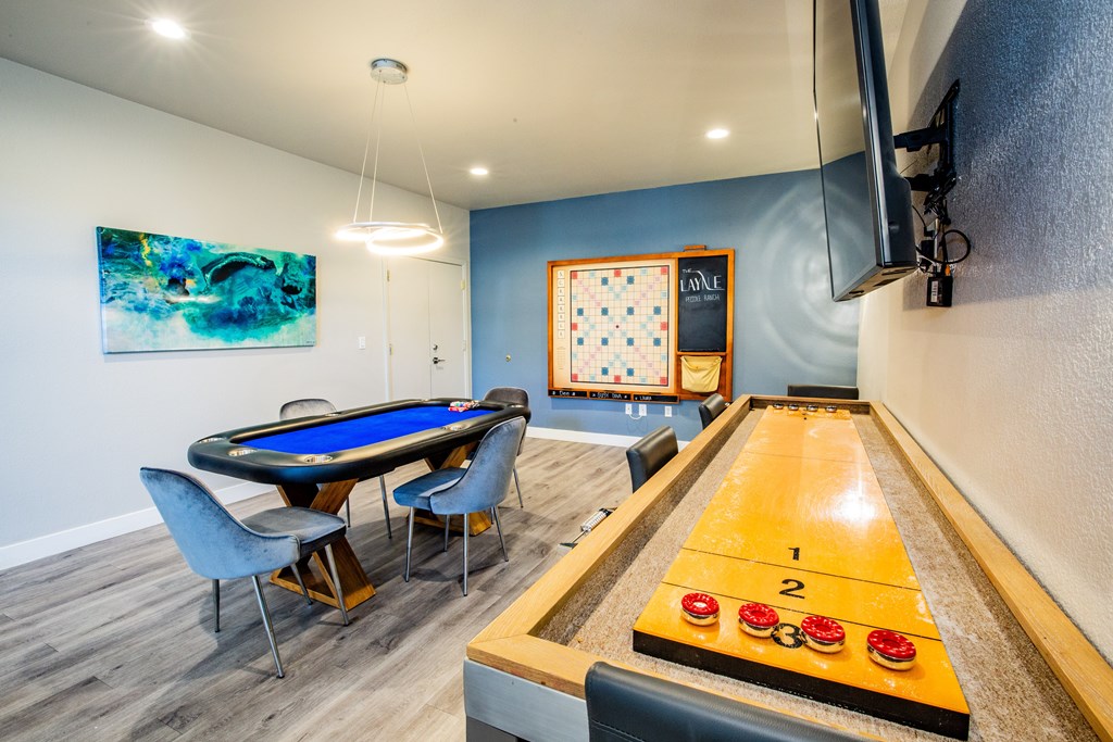 Game room with a felt table for card games, giant scrabble and shuffle board.