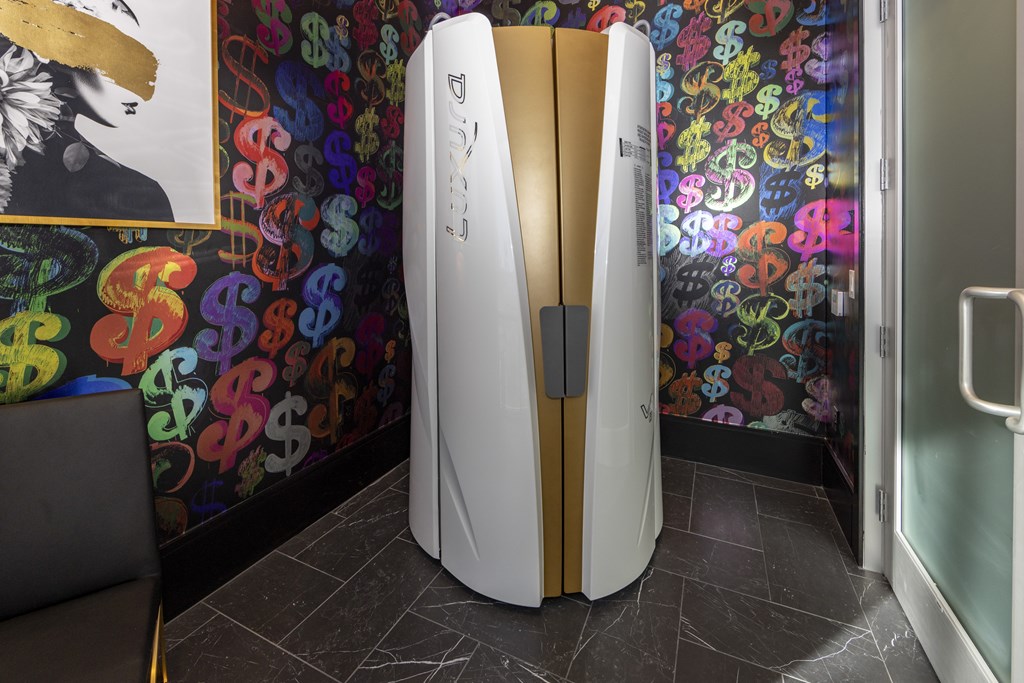A white and gold refrigerator in a room with a colorful wallpaper.