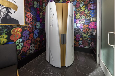A white and gold refrigerator in a room with a colorful wallpaper.