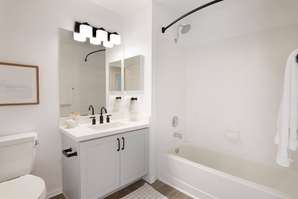 A white bathroom with a white tub, sink, and toilet.