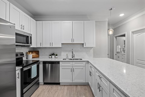 A modern kitchen with white cabinets and stainless steel appliances.