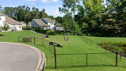 a park with a fenced in area and houses in the background