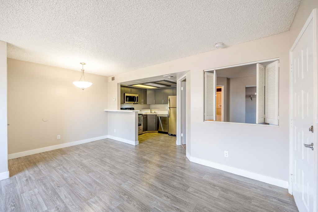 an empty living room with a kitchen in the background