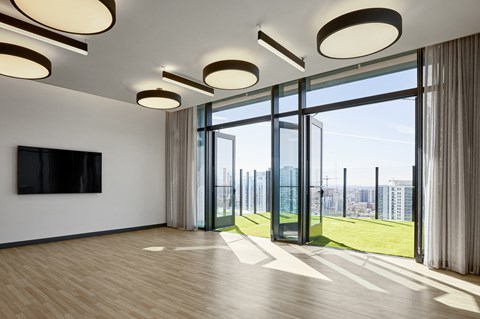Indoor empty space with large door with ceiling lighting, large windows and a view of the city