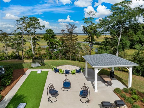 A covered patio area with a table and chairs overlooking a grassy field.