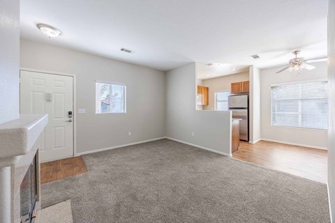 A spacious living room with a grey carpet and a ceiling fan.