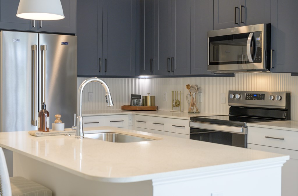 A modern kitchen with a white countertop and stainless steel appliances.