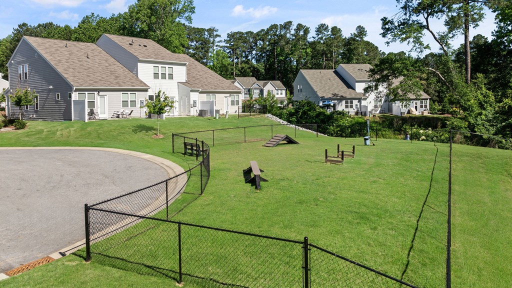 a fenced in dog park with houses in the background