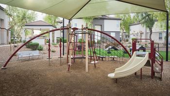 A playground with a slide, swings, and a seesaw.