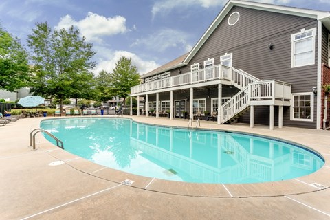 A large outdoor swimming pool with a deck and stairs leading to a building.