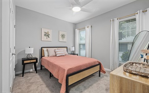 A bedroom with a bed, nightstand, and a painting on the wall.