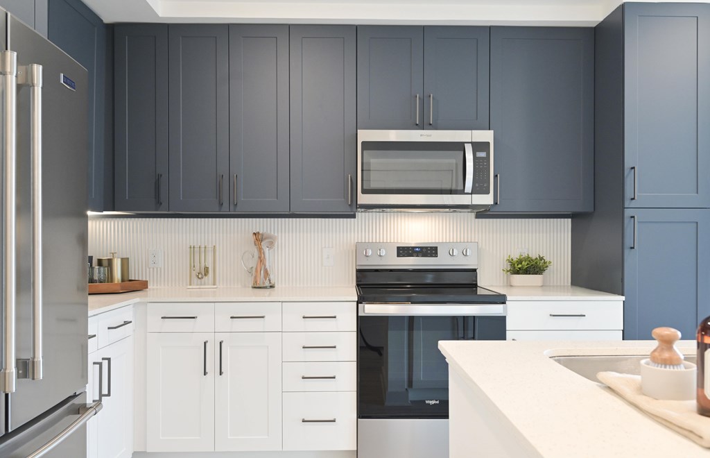 A modern kitchen with a stainless steel refrigerator and white countertops.