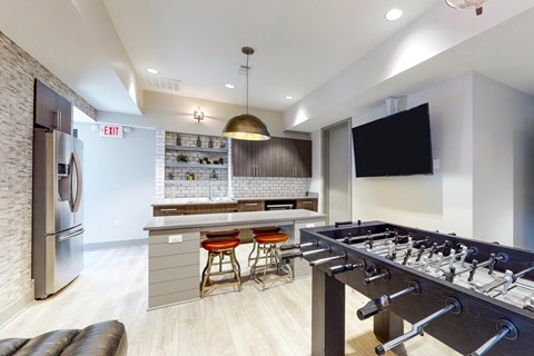 A modern kitchen with a foosball table in the middle.