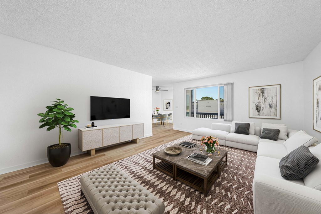 A living room with a white couch, a wooden coffee table, and a large window.