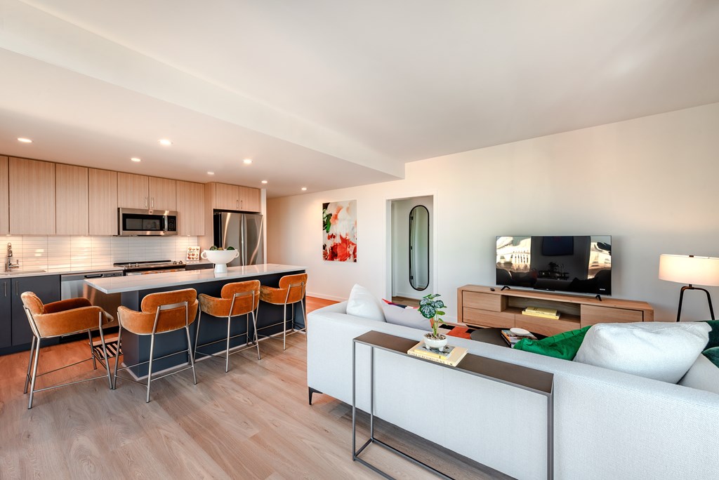 A modern living room with a white couch and a kitchen area in the background.
