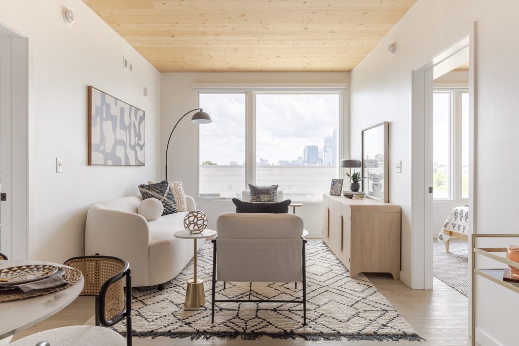 A living room with a white couch, a coffee table, and a large window.