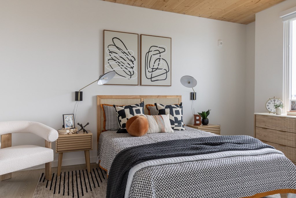 A bedroom with a bed, chair, and two wall art pieces.
