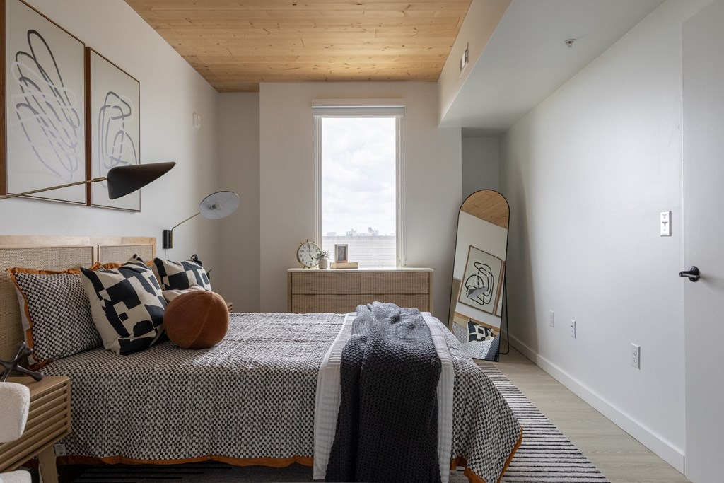 A bedroom with a bed, pillows, and a lamp.
