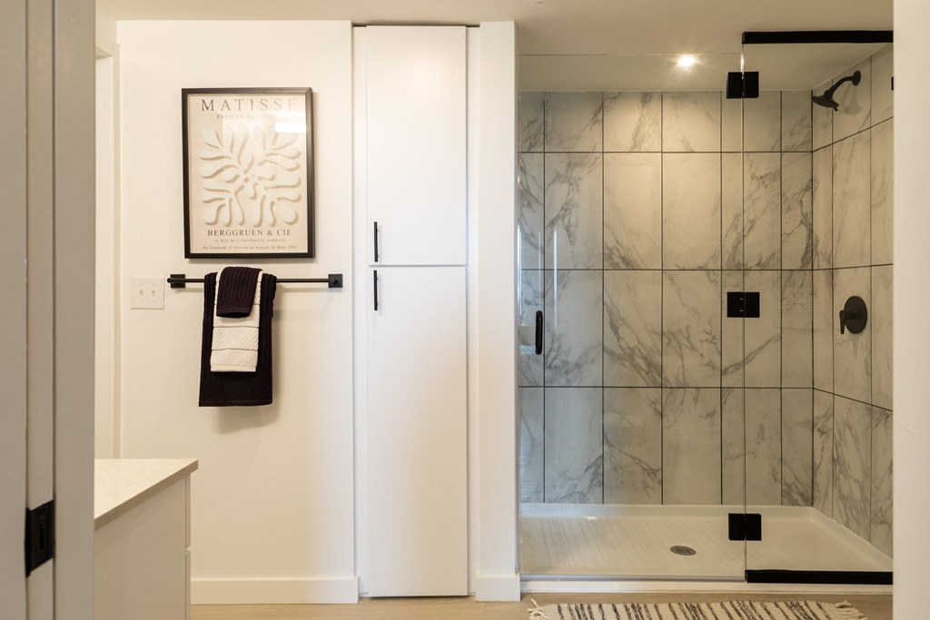 A bathroom with a marble tile shower and a white door.