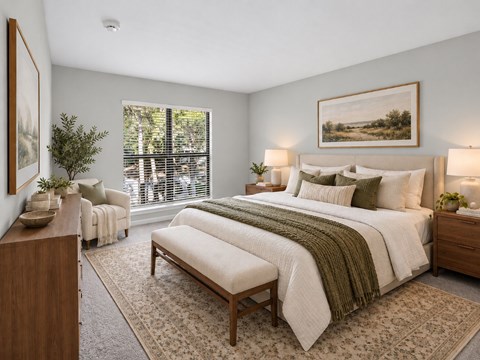 A bedroom with a large bed and a window with blinds.