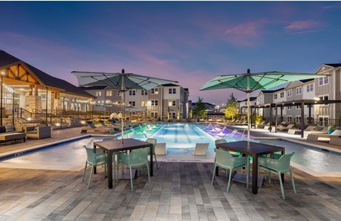 a rendering of a pool with tables and umbrellas at night