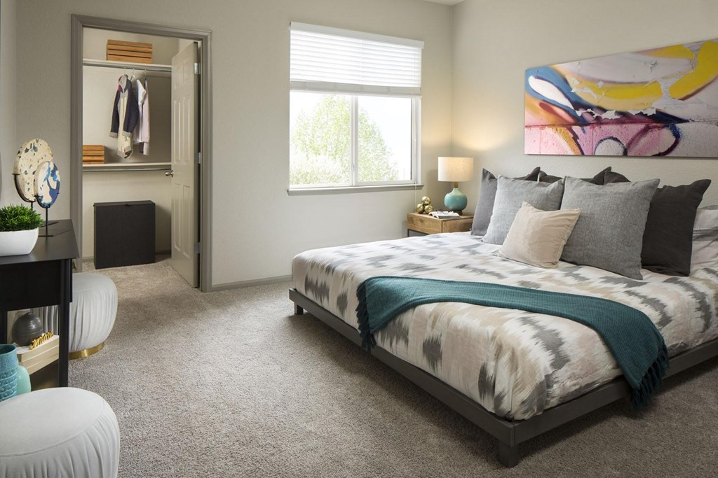 A bedroom with a large bed and a painting on the wall.