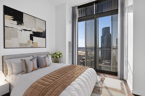 A bedroom with a large bed and a large window overlooking the city.