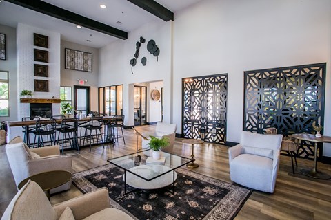 A living room with a glass coffee table and white chairs.