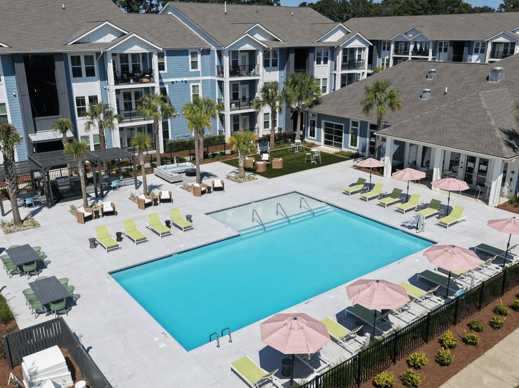 A large swimming pool surrounded by lounge chairs and umbrellas.