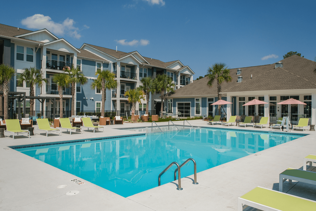 A large swimming pool in front of a building with a sunny day.