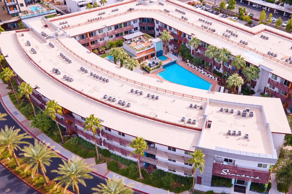 A large apartment complex with a pool and palm trees.