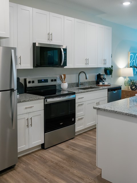 A modern kitchen with white cabinets and stainless steel appliances.