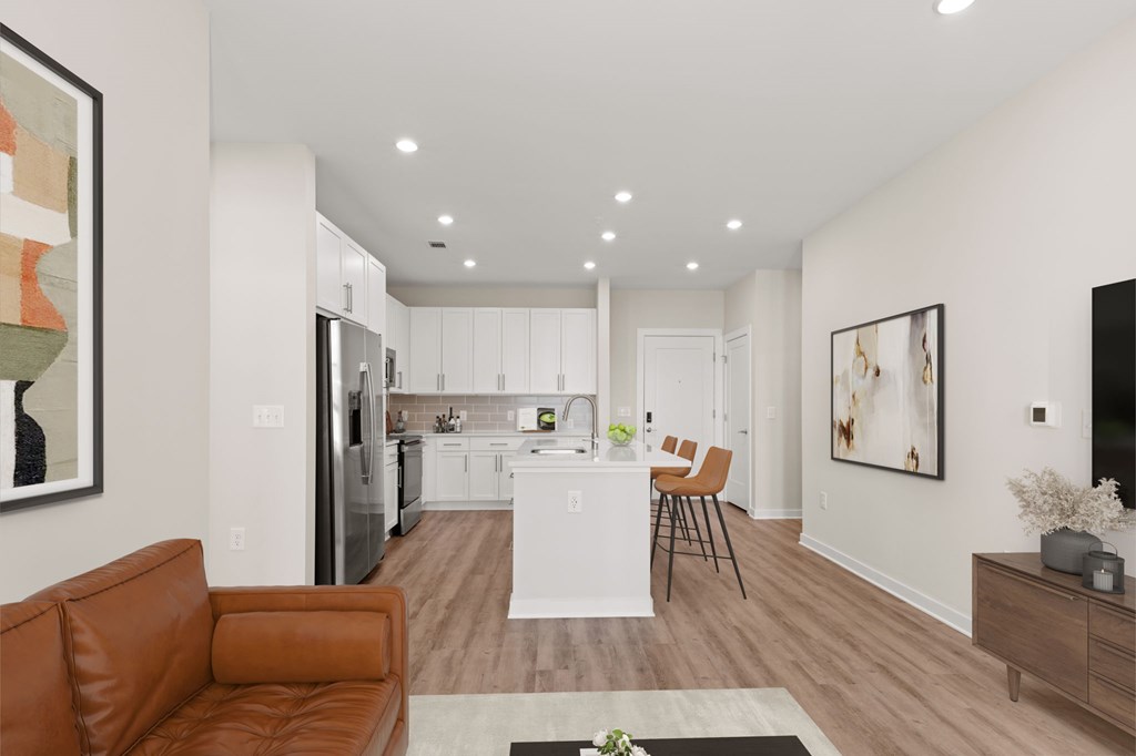 A modern living room with a brown leather couch and a kitchen in the background.