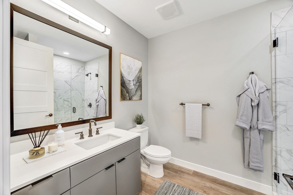 a bathroom with a toilet sink and shower with a glass door