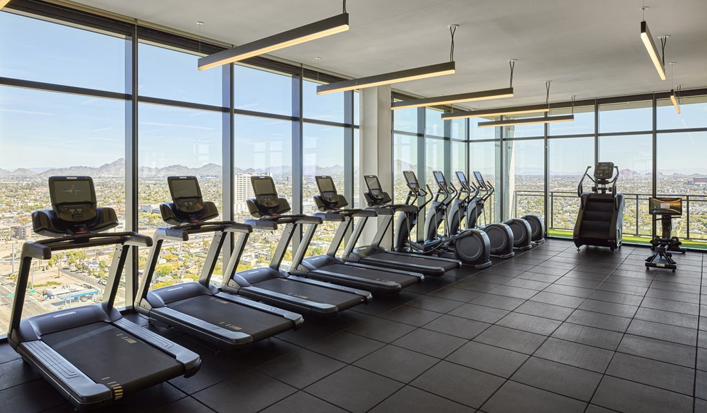 Fitness center with workout equipment, large windows, ceiling lighting