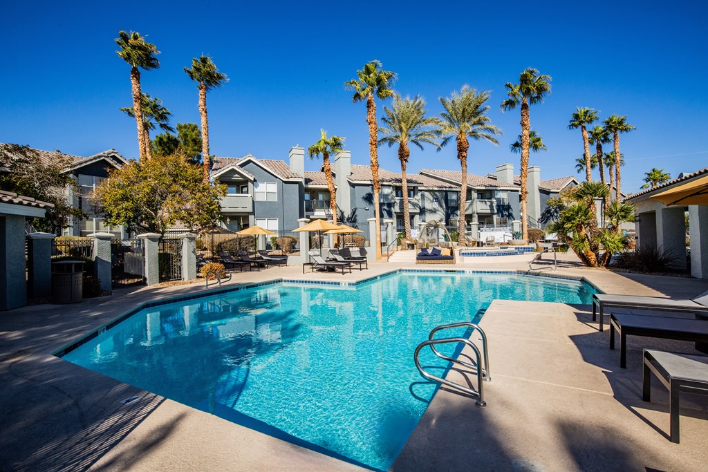 A swimming pool surrounded by palm trees and lounge chairs.