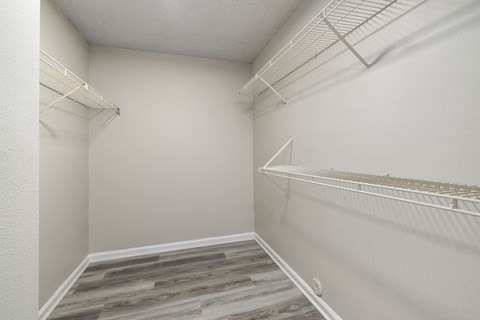 a spacious closet with white walls and shelves and a wood floor