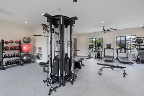 A spacious gym with a variety of equipment including a weight machine, a bench press, and a treadmill.