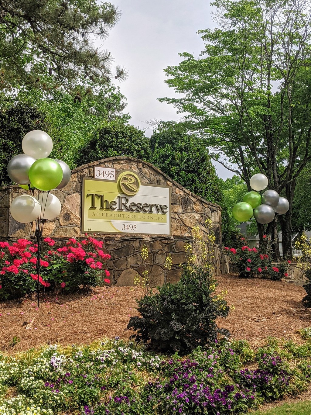 A sign for The Reserve surrounded by balloons and flowers.