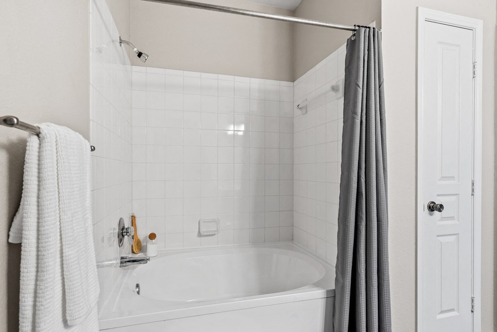 a white bathroom with a tub and a shower curtain