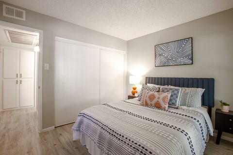 A bedroom with a large bed and a painting on the wall.