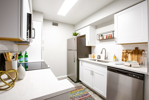A modern kitchen with white cabinets and a stainless steel refrigerator.